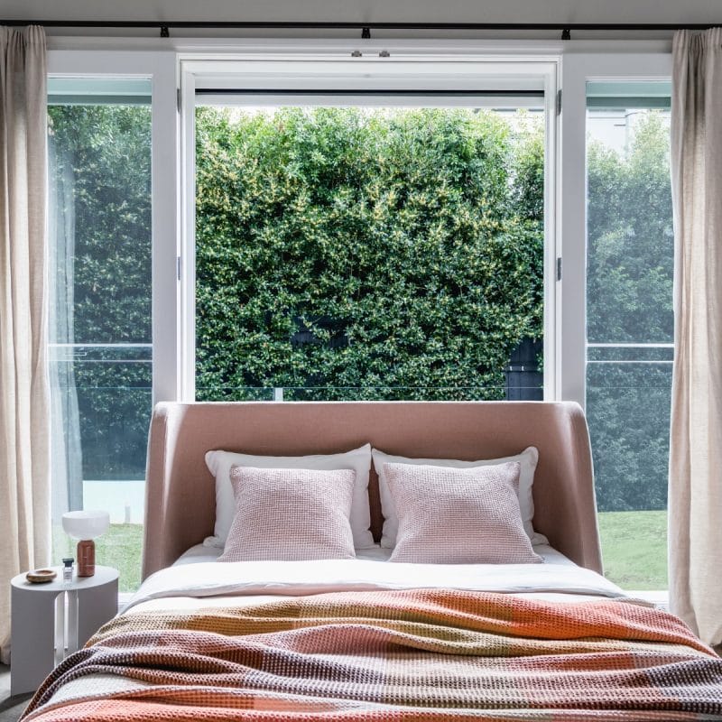 Curved linen bedhead with sculptural wingback design, upholstered in tactile fabric for a modern, cocoon-like sanctuary