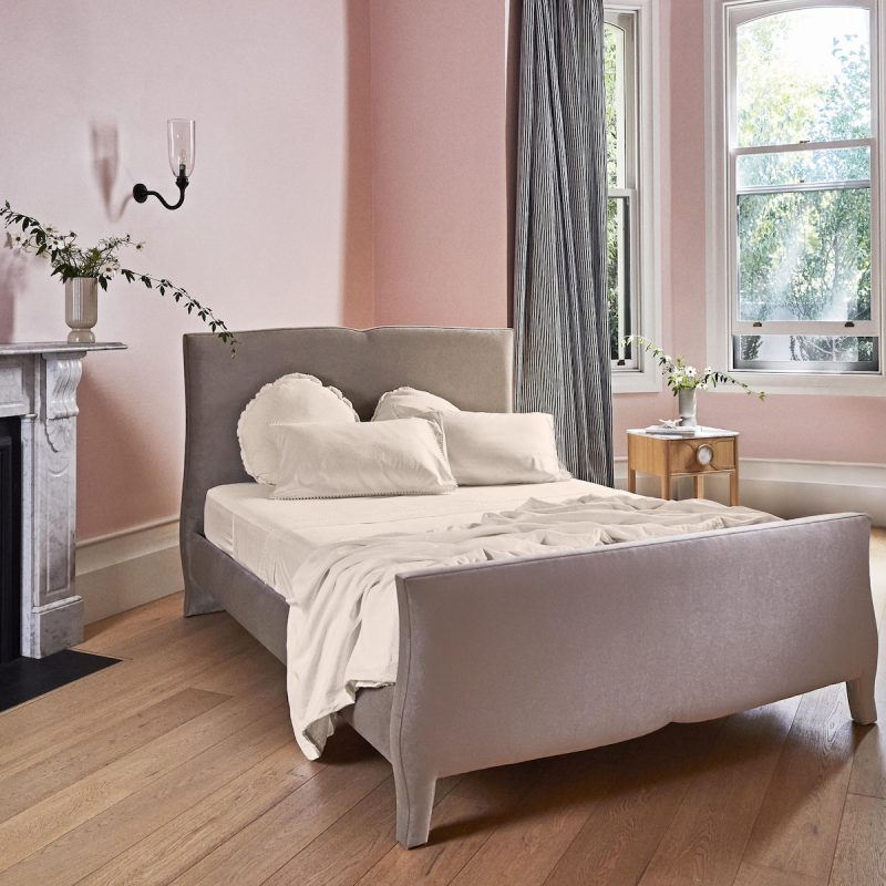 Grey velvet bed in pink bedroom with fireplace and flowers stripe curtains
