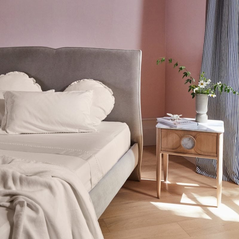 Grey velvet bed in pink room with fresh flowers