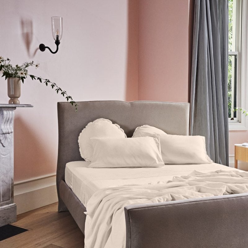 A bed with a gray frame and pink walls